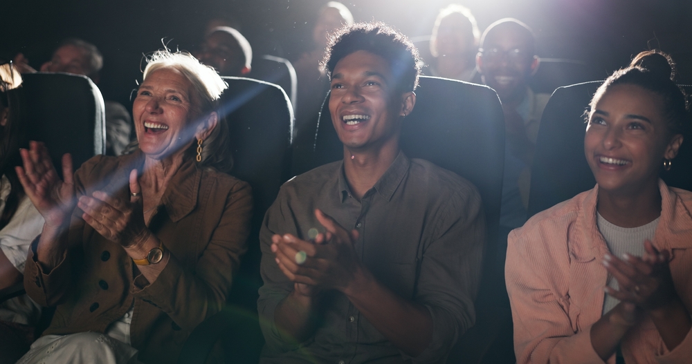 people sitting at a comedy show laughing and clapping