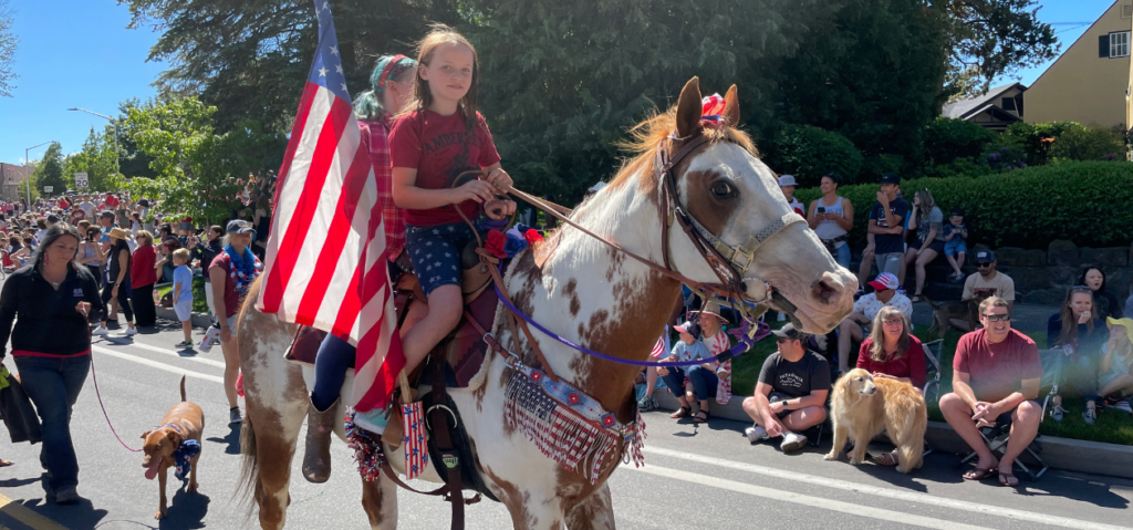 4th of july pet parade two children riding horse with american flag